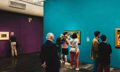 Visitors viewing paintings in a gallery with turquoise and purple walls in São Paulo