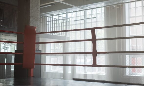 Empty boxing ring in a bright gym with tall windows