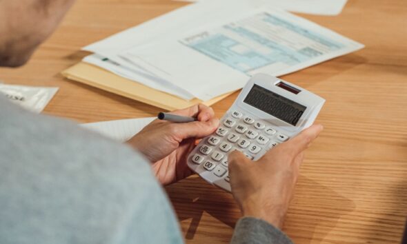 Hands using a calculator beside financial paperwork on a desk