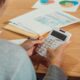 Hands using a calculator beside financial paperwork on a desk