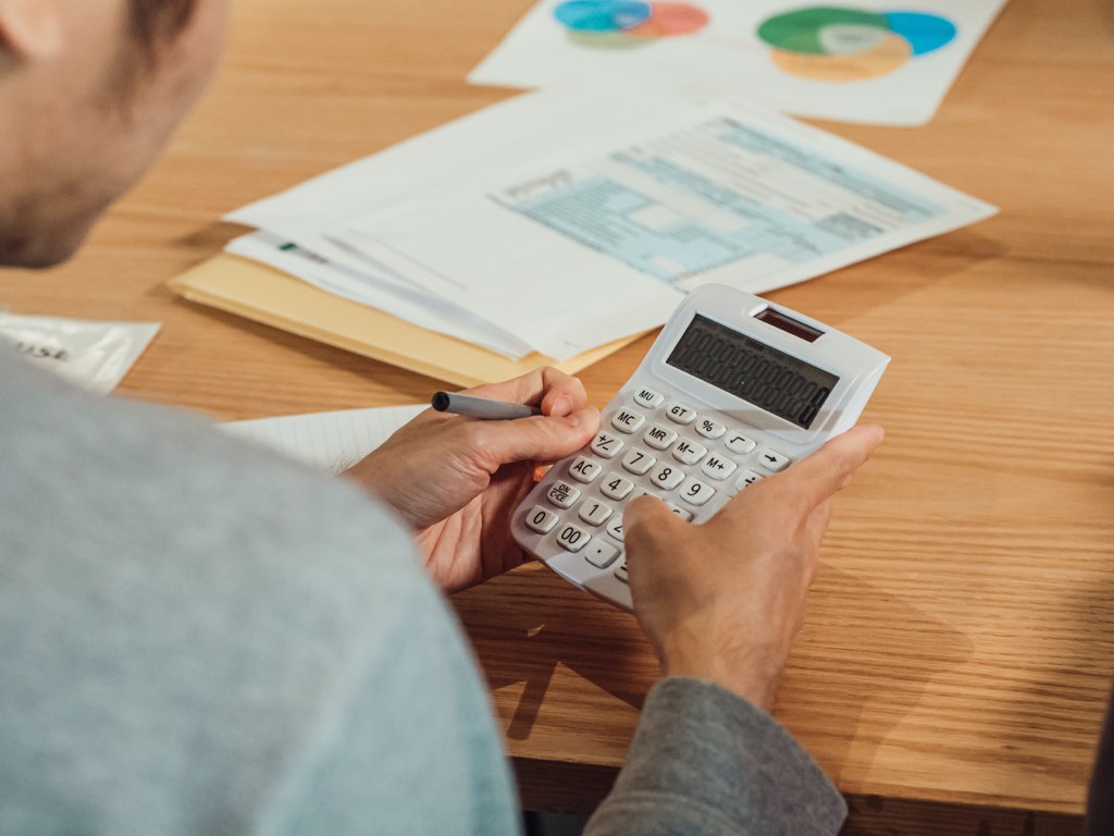 Hands using a calculator beside financial paperwork on a desk