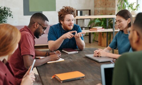 Adults discussing documents around a wooden meeting table