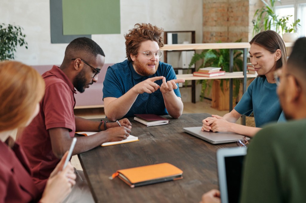 Adults discussing documents around a wooden meeting table