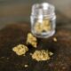 Dried cannabis flowers beside a glass jar