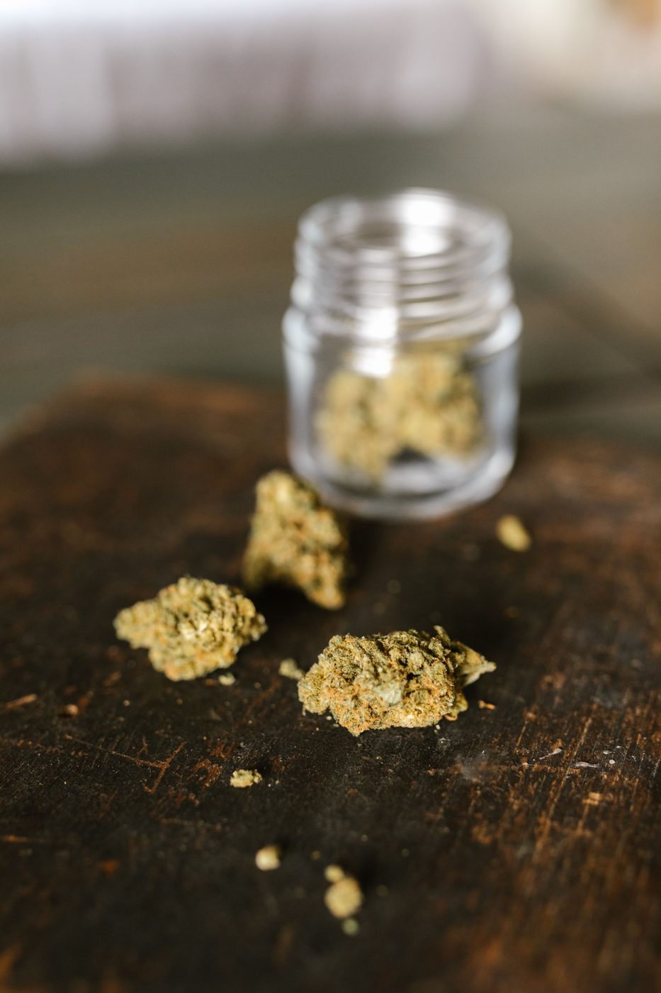 Dried cannabis flowers beside a glass jar