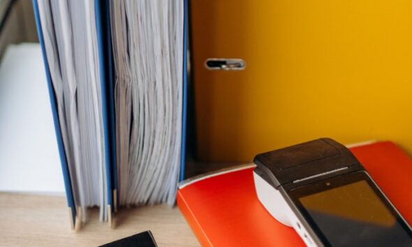Calculator and payment terminal beside upright office binders