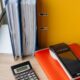 Calculator and payment terminal beside upright office binders