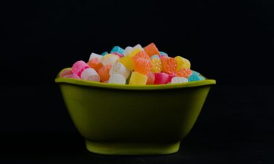 Colorful gummy candies in a green bowl against a dark background
