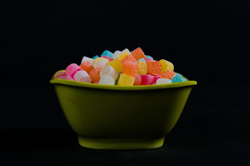 Colorful gummy candies in a green bowl against a dark background