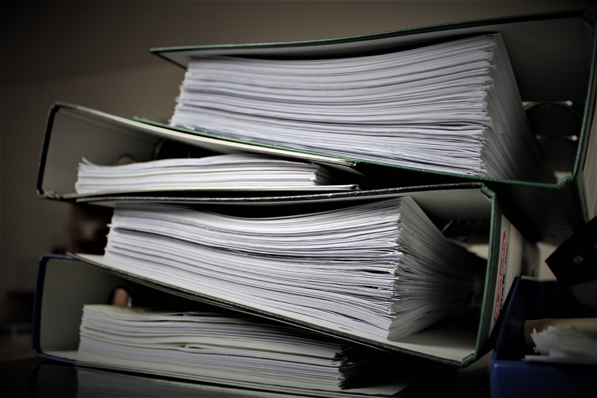 A stack of dark ring binders filled with paperwork