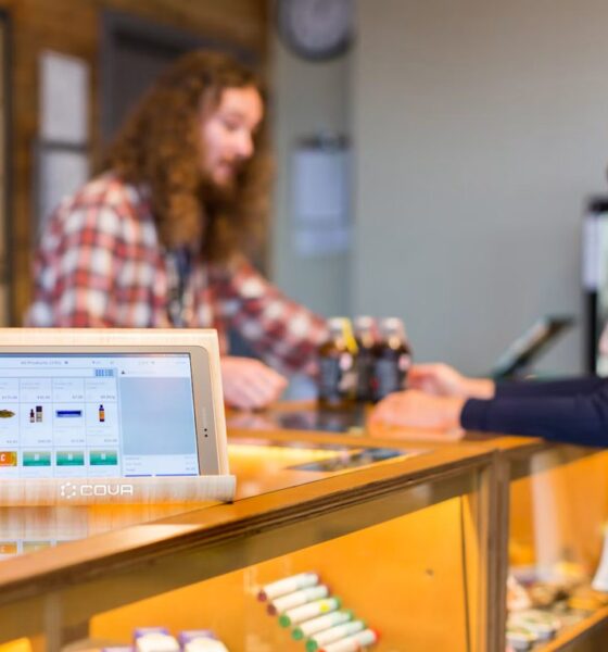 Point-of-sale screen on a cannabis dispensary counter with people in the background