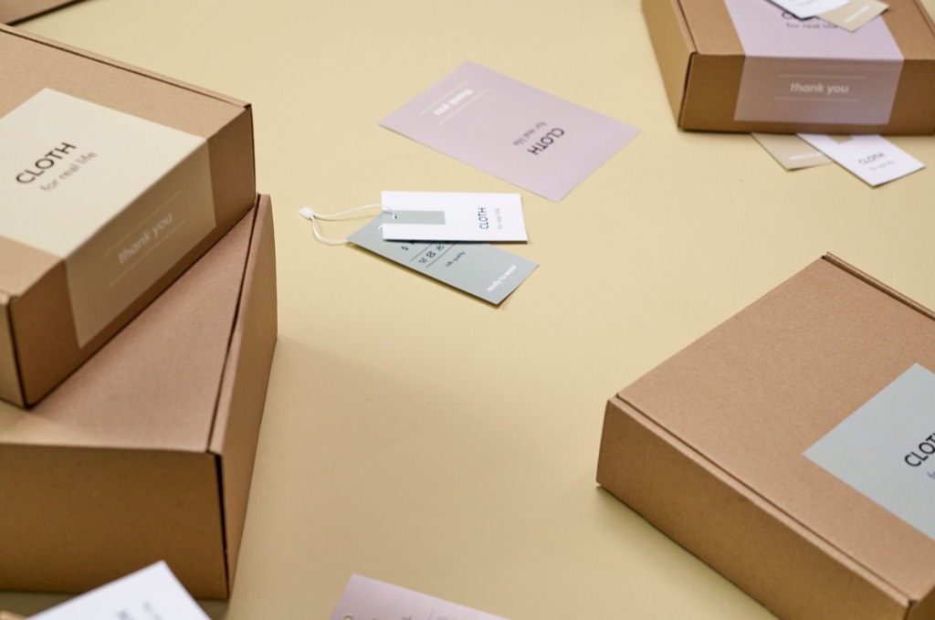 Plain cardboard boxes with white labels on a yellow surface