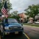 Small-town main street with American flags and parked vehicles