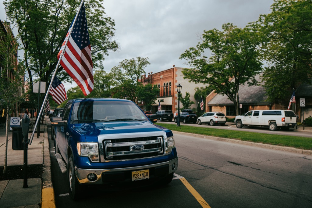 Small-town main street with American flags and parked vehicles