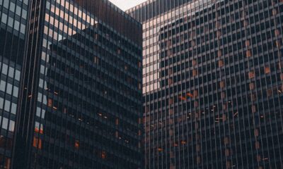 Glass office buildings viewed from below against a pale sky