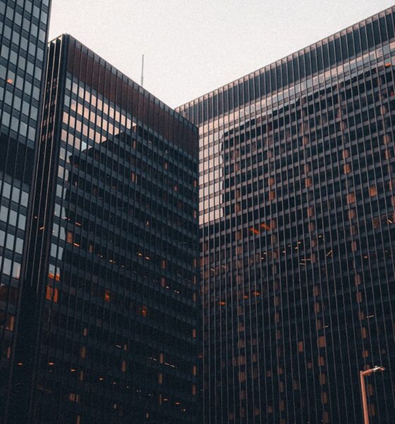 Glass office buildings viewed from below against a pale sky