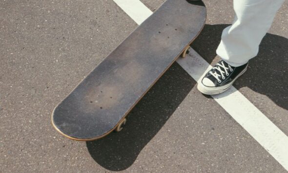 Sneakers and skateboard on a dark asphalt road