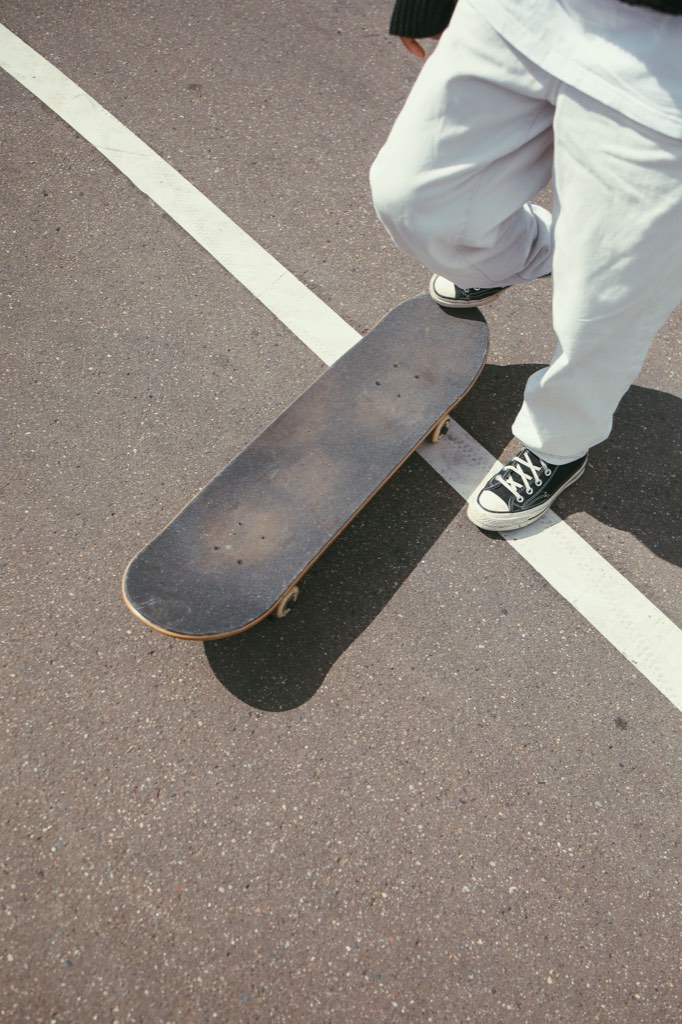 Sneakers and skateboard on a dark asphalt road