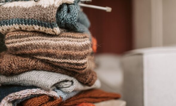 Folded knitted garments with knitting needles resting on top