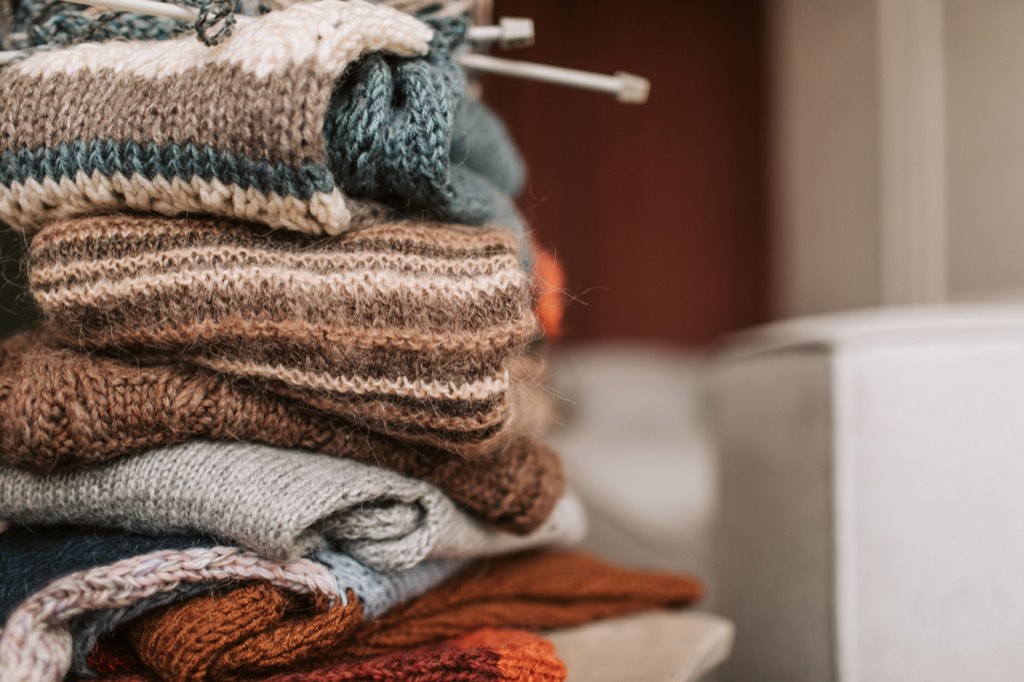 Folded knitted garments with knitting needles resting on top